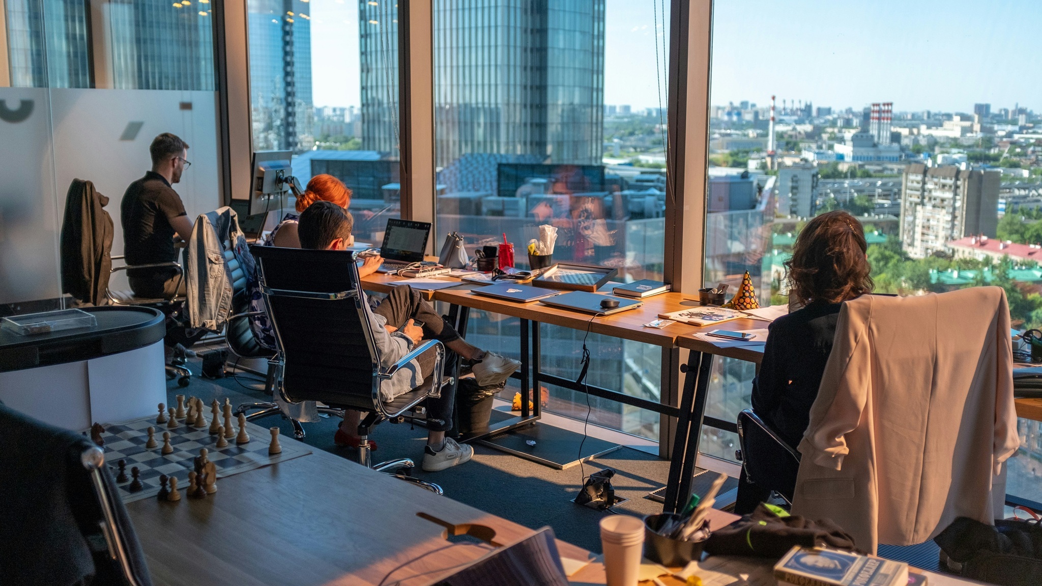 Modernes Grossraumbüro mit Panoramablick – Mitarbeitende arbeiten flexibel im Sinne von New Work am Laptop.